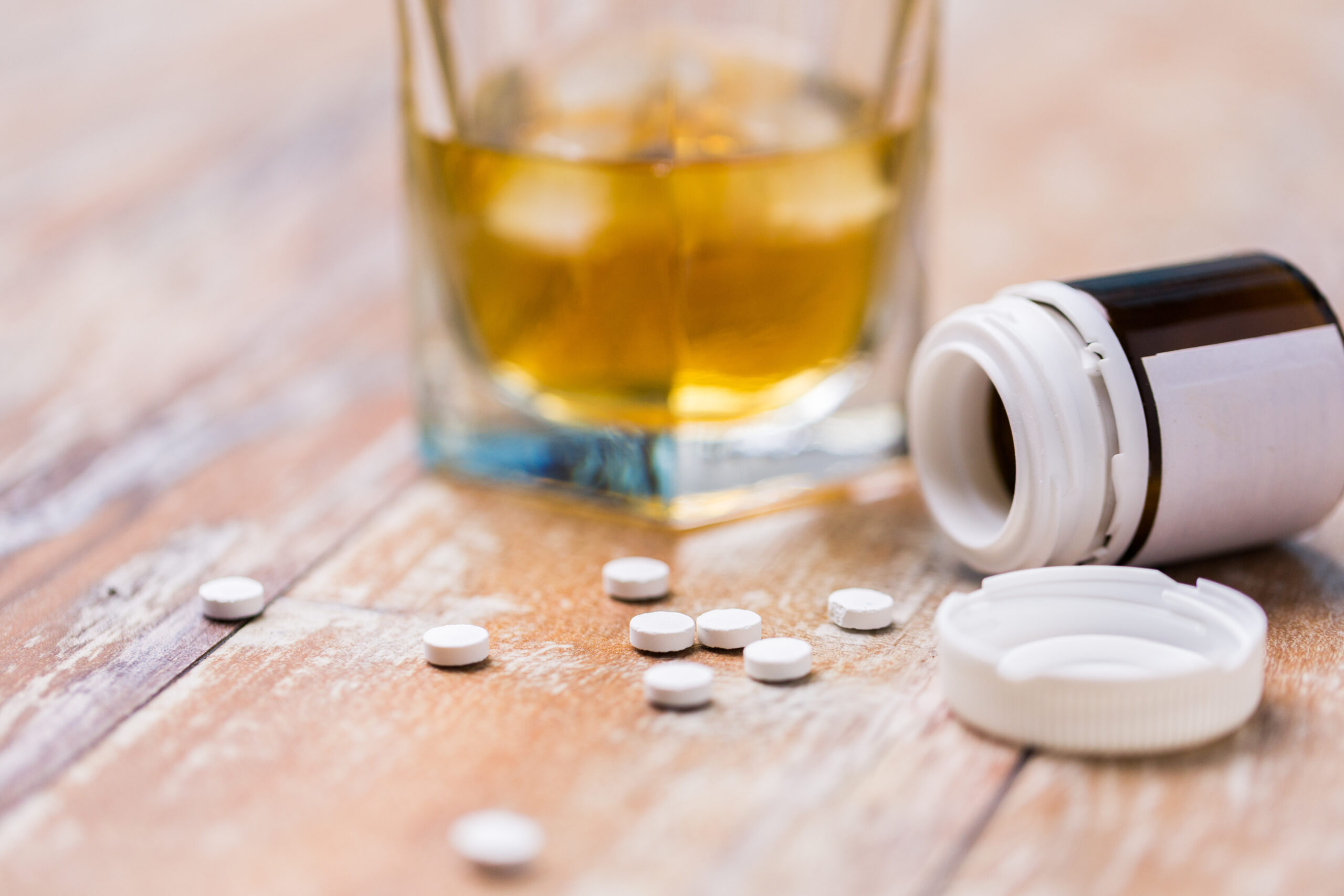Alcohol in a cup and pills on the counter